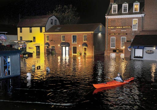 In this October 2012 photo, Jim Davis kayaks through waters flooding Bowen's Wharf after Superstorm Sandy in historic Newport, R.I. With scientists forecasting sea levels to rise by anywhere from several inches to several feet by 2100, historic structures and coastal heritage sites around the world are under threat.