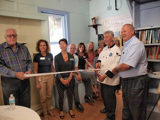 Rusty Kerver, St. Francis House Kitchen Manager, cuts the ribbon for the new kitchen with St. Johns Rotary Club representatives, St. Francis House staff and board members and Chamber of Commerce Ambassadors.