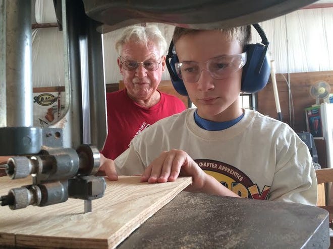 Mentor Larry Hill oversees Christian Behm as he cuts wood for a mini-most hydroplane boat, based from 1950s plans. They are among other mentors and youths in the Sunnyland Chapter Apprentice Mentoring Program for Youth (SCAMPY), part of the Tavares-based Sunnyland Antique Boat Club.