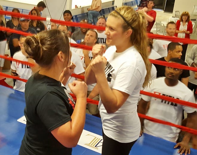 Bailiff Erin Filbert [l] faces off against Jacksonville Naval Air Station firefighter Elizabeth Vopper for photos after both did the traditional Guns N' Hoses pre-fight weigh-in on Tuesday, April 12, at Rebounderz in Bayard.