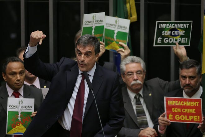 Brazil's Attorney General Jose Eduardo Cardozo, backed by posters behind that say in Portuguese "Impeachment without a crime is a coup," defends Brazil's President Dilma Rousseff during a debate on impeaching her in the Chamber of Deputies in Brasilia, Brazil, Friday, April 15, 2016. The lower chamber of Brazil's Congress began the debate on whether to impeach Rousseff, a question that underscores deep polarization in Latin America's largest country and most powerful economy. (AP Photo/Eraldo Peres)