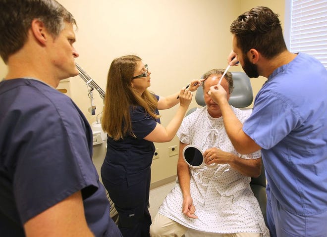 Dr. Jon Ward, left, looks on as Lina Noueilaty and Richard Nonzoque prep Barry Newton for a hair transplant procedure at the Hair Transplant and Restoration Center in Panama City on Friday.