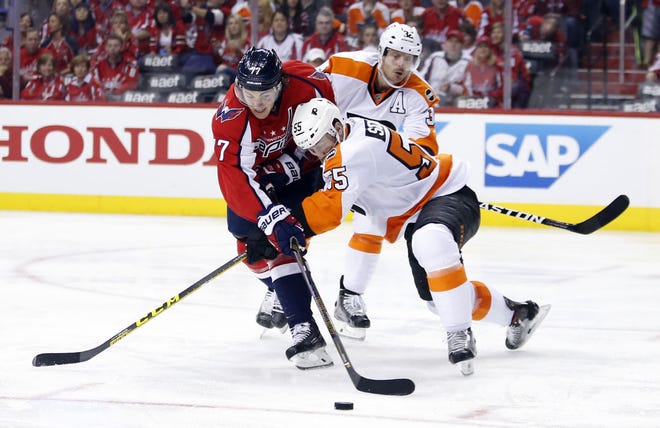 Washington's T.J. Oshie battles Philadelphia's Nick Schultz for the puck as Flyers defenseman Mark Streit trails the play in the second period of Game 2 on Saturday, April 16, 2016, in Washington. The Capitals won 4-1.