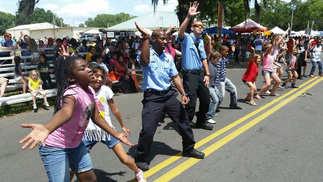 Fruitland Park firefighters Clarence Williams, left, and Tyler Ramsey leads a line dance to the song, “Watch Me Whip Nae Nae,” in the middle of Berckman Street in the annual Fruitland Park Day on Saturday.
