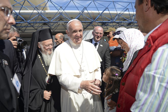 Pope Francis, flanked by Ecumenical Patriarch Bartholomew I, spiritual leader of the worldís Orthodox Christians, greet a group of refugees at the airport of Mytilene on the Greek island of Lesbos, Saturday, April 16, 2016. Pope Francis gave Europe a provocative and concrete lesson in how to treat refugees Saturday by bringing home 12 Syrian Muslims aboard his charter plane after an emotional visit to the hard-hit Greek island of Lesbos. (Filippo Monteforte/Pool Photo via AP)