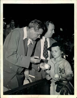 Babe Ruth autographs baseballs for 10-year-old Veronica Meehan during a visit to Shibe Park on July 28, 1947. Meehan was bat girl and mascot for Philadelphia 30th police district PAL baseball team. That day, she was Philly's official hostess for Ruth.