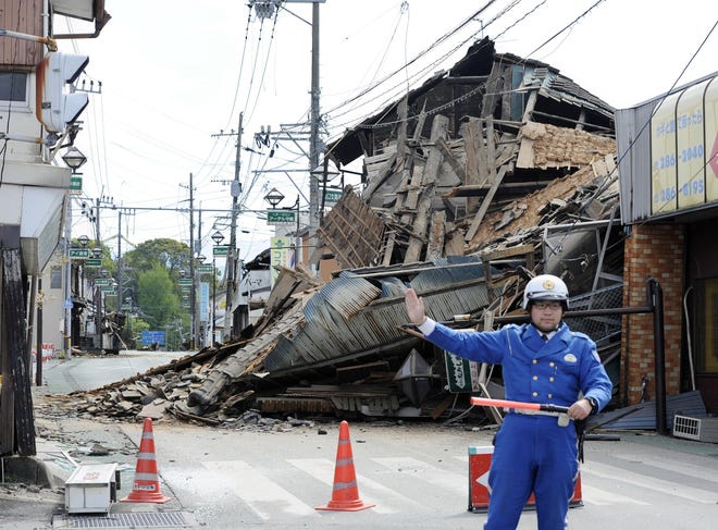 A police officer stands guard in front of a house destroyed by an earthquake in Mashiki, Kumamoto prefecture, southern Japan Saturday, April 16, 2016. A powerful earthquake struck southern Japan early Saturday, barely 24 hours after a smaller quake hit the same region. (Ryosuke Uematsu/Kyodo News via AP) JAPAN OUT, MANDATORY CREDIT