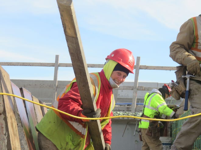 Pamela LeDoux, a laborer for ET&L Corp. of Stow, lifts a 2-by-4 while working on a job site alongside male construction workers in Methuen. Submitted Photo