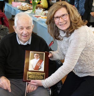 World War II Veteran John Seymour, known as "Deacon Jack" at St. Francis of Assisi Parish in Newburgh, was honored recently when the food pantry he established was renamed for him. His daughter Jeannine shows off his plaque. PHOTO BY JAMES D. PELOSO