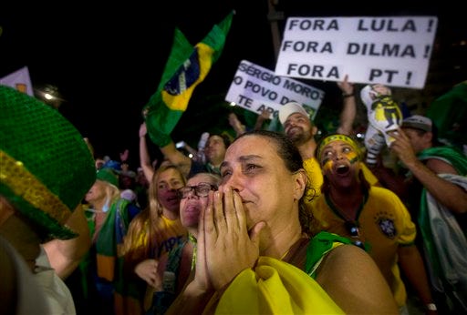 Anti-government demonstrators celebrate after the lower house of Congress voted to impeach Brazil's President Dilma Rousseff, on Copacabana beach in Rio de Janeiro, Brazil, Sunday, April 17, 2016. The measure now goes to the Senate. Rousseff is accused of using accounting tricks in managing the federal budget to maintain spending and shore up support. The signs behind read in Portuguese: "Get out Dilma! Get our Lula! Get out Workers Party!" (AP Photo/Silvia Izquierdo)
