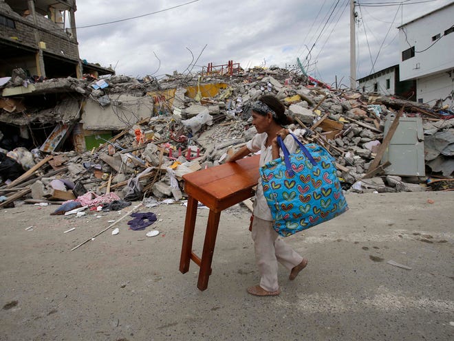 A woman carries a table through the street after an earthquake in Pedernales, Ecuador, Sunday, April 17, 2016. Rescuers pulled survivors from the rubble Sunday after the strongest earthquake to hit Ecuador in decades flattened buildings and buckled highways along its Pacific coast on Saturday.