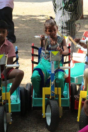 A child in Gujarat, India, who does not have a the use of her legs receives a hand-cranked cart that was built by PET West Michigan in Holland. Contributed