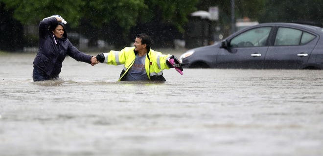 Alberto Lopez, right, helps his wife Glenda wade through floodwaters as they evacuate their flooded apartment complex Monday, April 18, 2016, in Houston. Storms have dumped more than a foot of rain in the Houston area, flooding dozens of neighborhoods and forcing the closure of city offices and the suspension of public transit. (AP Photo/David J. Phillip)