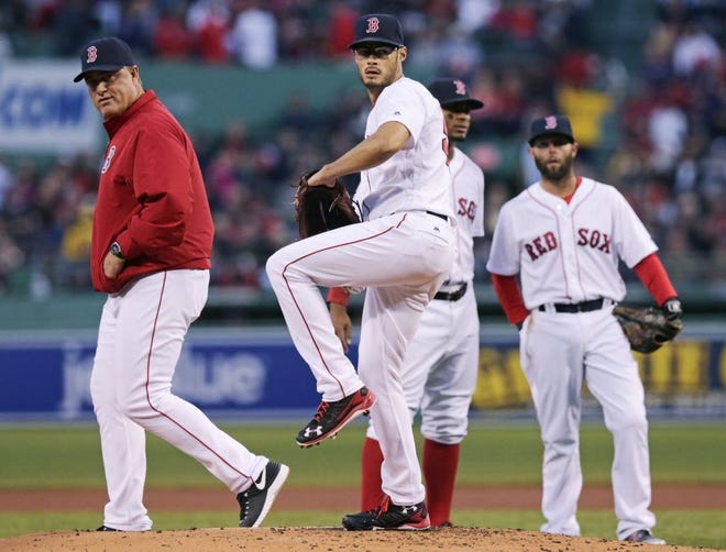 As John Farrell, left, watches, Joe Kelly tests his arm before leaving the game with an injury in the first inning.
