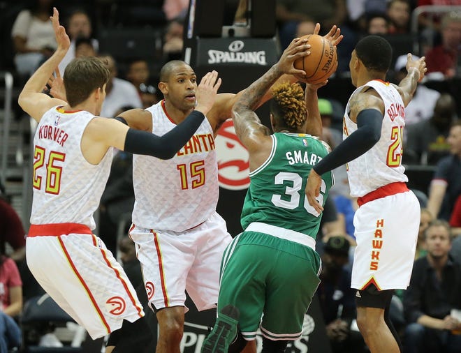 The Hawks' Kyle Korver, (26) Al Horford (15) and Kent Bazemore, right, triple team the Celtics' Marcus Smart during the first half of Tuesday's game in Atlanta. Curtis Compton/Atlanta Journal-Constitution via AP