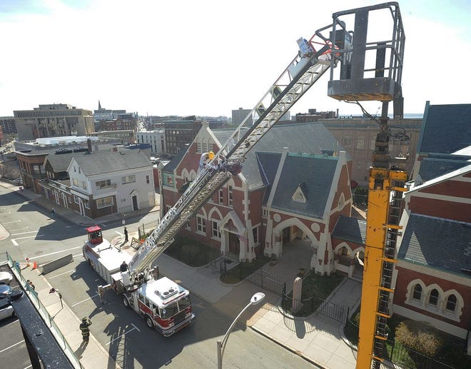 Fall River Ladder 4 firefighter Mike Souza rescues a bucket operator four stories over Rock Street late Thursday afternoon. The machine got stuck opposite the Family Services top floor.