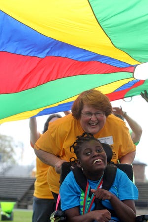 Volunteer Anesia Bridges and athlete Michelle Lamar participate in the parachute umbrella event at Special Olympics in 2015. (Star file photo)