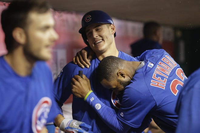 Chicago Cubs' Anthony Rizzo, center, celebrates in the dugout with Jason Heyward (22) after hitting a solo home run off Cincinnati Reds starting pitcher Jon Moscot during the fourth inning of a baseball game, Friday, April 22, 2016, in Cincinnati. (AP Photo/John Minchillo)