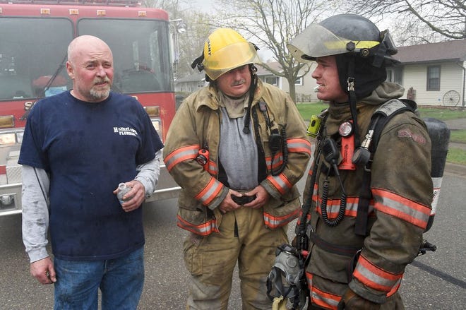Dundee volunteer firefighter Ron Justice, (left) owner of Hometown Plumbing on Monroe St., Dundee talks with his brother Dundee Lieutenant Rob Justice and his son Charles as firefighters from Dundee, Ida, Summerfield and Monroe Township extinguished the fire at Hometown Plumbing on Monroe St. Thursday. Charles Justice was an employee of his uncle Ron Justice (Monroe News photo by TOM HAWLEY)