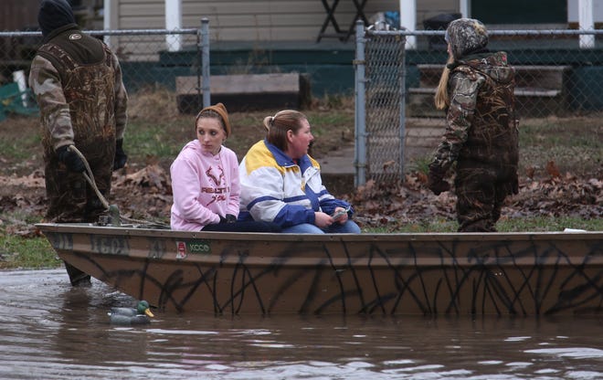 Annette Wilson, center, and her niece Brittany Wilson prepare to reach dry land while seated in a boat after being pulled through floodwaters by rescue volunteers Missy and A.J. Devault along Springfield Street in Kincaid on Wednesday, Dec. 30, 2015. David Spencer/The State Journal-Register