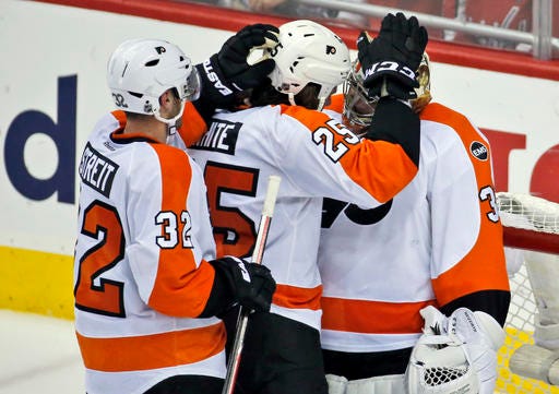 Philadelphia Flyers defenseman Mark Streit (32), from Switzerland; center Ryan White (25) and goalie Michal Neuvirth (30), from the Czech Republic, celebrate after Game 5 in the first round of the NHL Stanley Cup hockey playoffs against the Washington Capitals, Friday, April 22, 2016, in Washington. The Flyers won 2-0. (AP Photo/Alex Brandon)