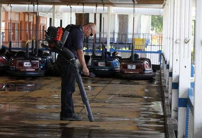 Gary Phillips, an employee at Joyland Amusement Park, cleans water out of the bumper cars arena. The park was shut down to clean up after flooding that occurred in late May 2015.