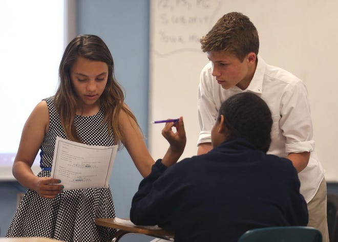 Kyra Kooley and Todd Harris help Amaya Bazemore with a math problem Tuesday at North Bay Haven Middle School.