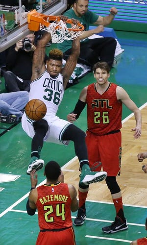 Boston Celtics' Marcus Smart slams for two points over Atlanta Hawks defenders Kent Bazemore and Kyle Korver during the fourth period in Game 4 of a first-round NBA basketball playoff series in Boston on Sunday, April 24, 2016. Boston won, 104-95, in overtime.