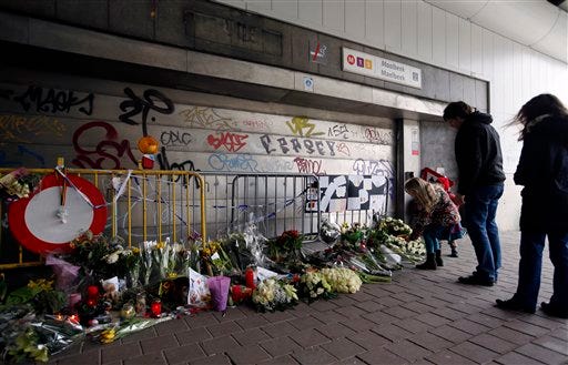 FILE - In this Saturday, March 26, 2016 file photo, people stop and look at floral tributes placed outside the Maelbeek metro station, the scene of one of the bomb attacks on the Belgian capital, in Brussels. The subway station in the Belgian capital where a suicide bomber killed 16 people a month ago will reopen Monday, April 25, 2016. The Brussels regional transit authority, commonly known as the STIB, announced the reopening Friday, April 22 on social media. (AP Photo/Alastair Grant, file)