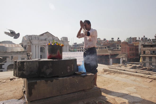 A Nepalese man offers prayers in front of a 'Siva Lingam', symbolic of Hindu god Shiva, as he worships at a temple that was completely destroyed in last year's earthquake at the Basantapur Durbar Square in Kathmandu, Nepal, Sunday, April 24, 2016. Government officials, diplomats and ordinary people gathered at the remains of a fallen iconic tower in the Nepalese capital on Sunday to mark the anniversary of a devastating earthquake that killed thousands and injured many more in the Himalayan nation. (AP Photo/Niranjan Shrestha)