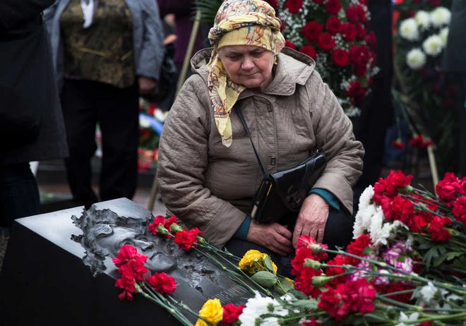 Nataliya Khodemchyuk, 64, from Ukraine, a widow of Chernobyl liquidator Valery Khodemchyuk, sits at his grave at the Mitino Cemetery in Moscow, during a ceremony on the 30th anniversary of the explosion at the Chernobyl nuclear power plant, Tuesday, April 26, 2016. About 600,000 people, often referred to as Chernobyl's "liquidators," were sent in to fight the fire at the nuclear plant after an explosion on April 26, 1986. (AP Photo/Pavel Golovkin)
