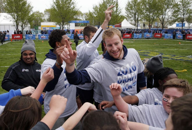 North Dakota State's Carson Wentz, huddling with children during an NFL Play 60 event at Grant Park in Chicago on Wednesday, is expected to be taken by the Eagles with the second overall pick in Thursday night's first round of the NFL Draft.