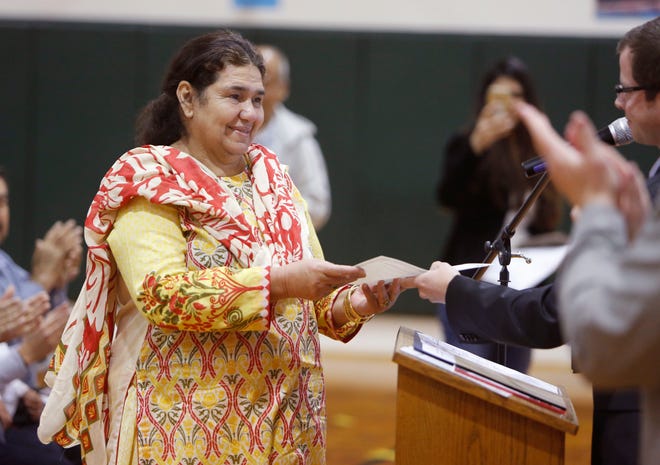 Asmat Begum, from Pakistan, receives her citizenship certificate from U.S. Citizenship and Immigration Services Field Office Director Mark Siegl during a naturalization ceremony at Ida Freeman Elementary School in Edmond. [Photo by Paul Hellstern, The Oklahoman]