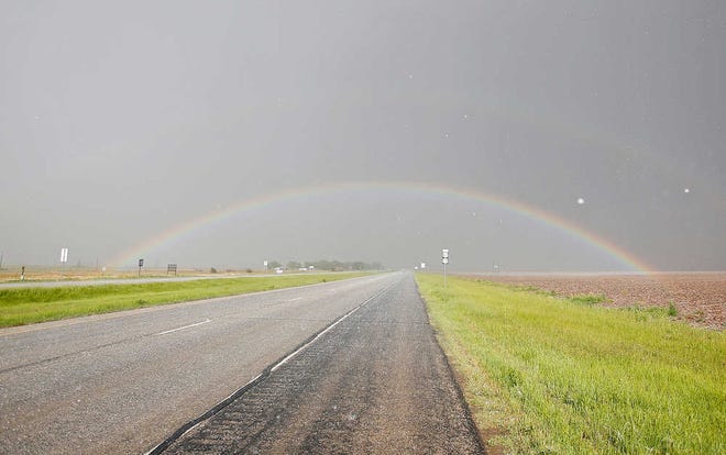 A rainbow appears in the sky while hail falls on the road during a storm near Floydada on Thursday.