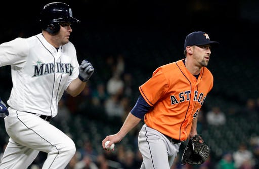Closing pitcher Houston Astros' Luke Gregerson, right, tosses the ball to first after fielding a grounder from Seattle Mariners' Seth Smith, left, to complete the first out of the bottom of the ninth inning of a baseball game Wednesday, April 27, 2016, in Seattle. The Astros won 7-4. (AP Photo/Elaine Thompson)