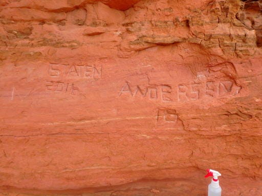 In this April 15, 2016, photo, released by the National Park Service shows carved graffiti at Frame Arch at Arches National Park. Officials at Utah's Arches National Park are investigating large graffiti so deeply carved into one of the park's famous red rock arches that it might be impossible to erase. (Alice deAnguera/National Park Service via AP)