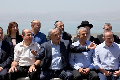 File - In this Sunday, April 17, 2016 file photo, Israeli Prime Minister Benjamin Netanyahu, center, poses with ministers prior to the weekly cabinet meeting in the Israeli controlled Golan Heights. Netanyahu has sparked a new diplomatic brushfire by declaring that the Golan Heights, seized from Syria in the 1967 war, is and should remain sovereign Israeli territory. But following some tough international criticism, Israeli officials have begun to backtrack, saying that a 1981 decision to apply Israeli law to the strategic plateau fell short of annexation and implying that Netanyahu misspoke. (AP Photo/Sebastian Scheiner, File)