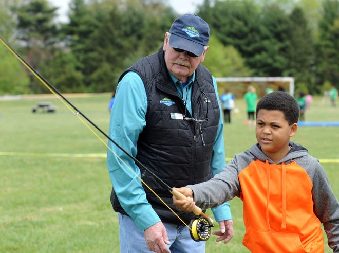 Bob Powell, of Clementon, an L.L. Bean fly fishing expert, shows Jonathan Leath Jr., 11, of Moorestown, how to cast during YMCA Healthy Kids Day on Saturday, April 30, 2016, in Mount Laurel.