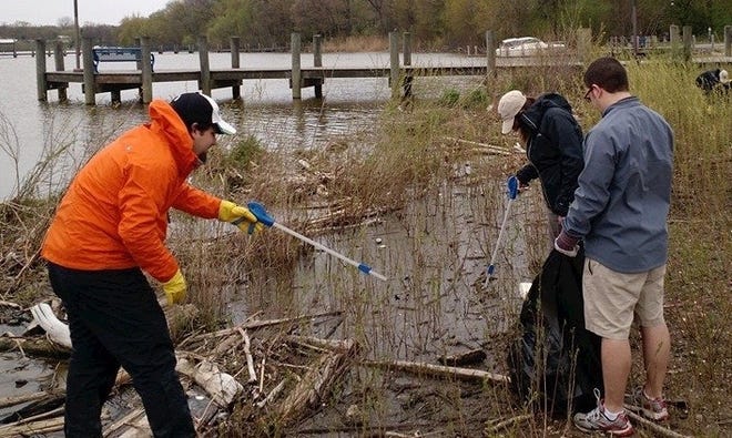 Greenway Manager Dan Callam, left, reaches for a piece of trash near Dunton Park in Holland. The Outdoor Discovery Center organized a river cleanup on Saturday afternoon, April 30. The cold, rainy weather kept the cleanup small, one of the event's organizers said, but Discovery Center staff and a few volunteers managed to collect several bags of trash, a large tire and even a full mail box during their walk along the water. The Discovery Center will host another river cleanup event in September. Contributed