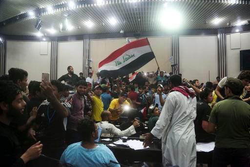 Supporters of Shiite cleric Muqtada al-Sadr storm parliament in Baghdad's Green Zone, Saturday, April 30, 2016. Dozens of protesters climbed over the blast walls and could be seen storming the Parliament building, carrying Iraqi flags and chanting against the government. (AP Photo/Khalid Mohammed)