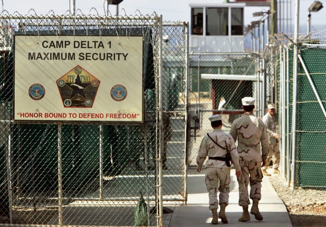 In this 2006 photo, U.S. military guards walk within the Camp Delta military-run prison at the Guantanamo Bay U.S. Naval Base, in Cuba. AP PHOTO