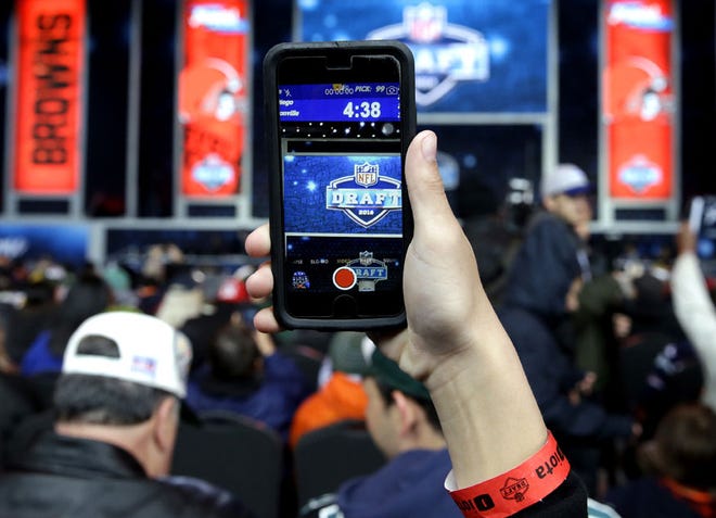 A fan takes photos of a big screen during the last day of the 2016 NFL Draft on Saturday, April 30, 2016, in Chicago. (AP Photo/Nam Y. Huh)
