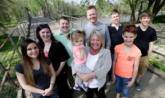 In this Tuesday, April 26, 2016 photo, Denise Moore, center, in white, of Des Moines, Iowa, poses with her family, from left, daughter Alex Gibbs, Emily Bosch, son Kodi Baughman, granddaughter MacKenzie Moore, sons Kori Moore, Kelli Moore, daughter Andy Gibbs, and son Kasi Baughman during a visit to Water Works Park, in Des Moines, Iowa. Moore, a mother of seven, nearly lost her parental rights after her arrest in 2003 for conspiracy to deliver methamphetamine. (AP Photo/Charlie Neibergall)