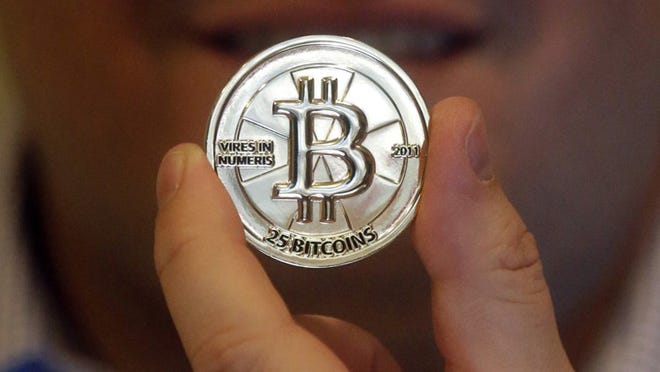 In this April 3, 2013 photo, Mike Caldwell, a 35-year-old software engineer, holds a 25 Bitcoin token at his shop in Sandy, Utah. Caldwell mints physical versions of bitcoins, cranking out homemade tokens with codes protected by tamper-proof holographic seals, a retro-futuristic kind of prepaid cash. With up to 70,000 transactions each day over the past month, bitcoins have been propelled from the world of Internet oddities to the cusp of mainstream use, a remarkable breakthrough for a currency which made its online debut only four years ago. (AP Photo/Rick Bowmer)