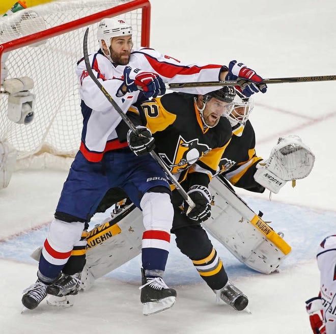 Washington's Daniel Winnik (from left) and Pittsburgh's Ben Lovejoy battle for position in front of the net while Penguins goalie Matt Murray looks for the puck in the third period of Game 3 on Monday.