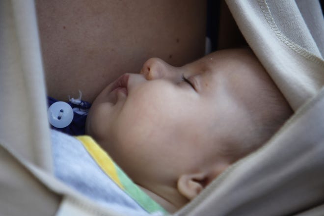 A baby sleeps in the arms of his mother after a mass breastfeeding in celebration of 2013 World Breastfeeding Week, in Thessaloniki, Greece. (Nikolas Giakoumidis/AP Photo)