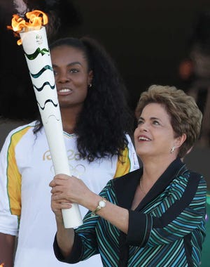 Brazil President Dilma Rousseff (right) holds the torch next to Olympic athlete Fabiana Claudino during torch-lighting ceremony at Planalto Presidential Palace, in Brasilia, Brazil on Tuesday.