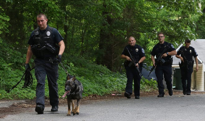 Police use tracking dogs to search along Venus Avenue for two suspects in an armed robbery of a convenience store on Bessemer City Road before noon Tuesday. PHOTO MIKE HENSDILL/THE GAZETTE
