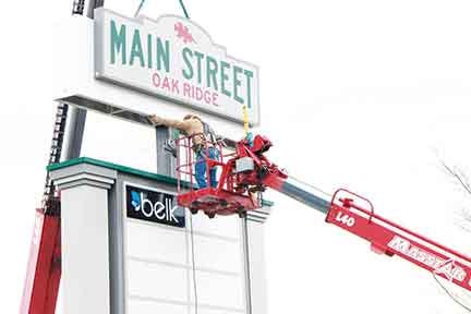 Workers hang the sign for Main Street Oak Ridge earlier this year.