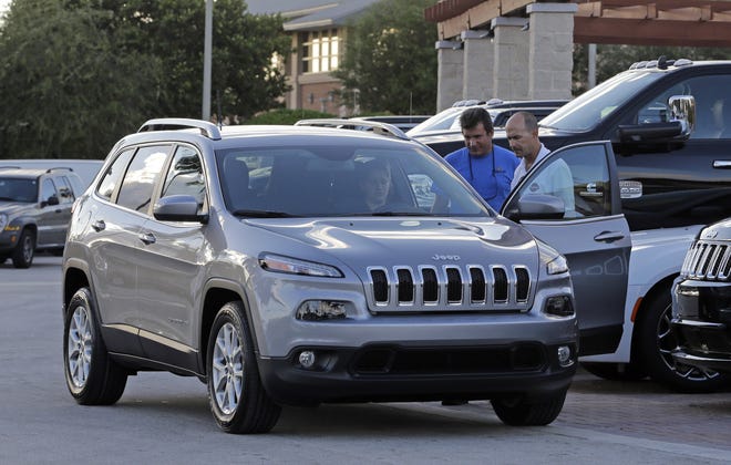 Salesperson Jerry Camero, right, delivers a 2016 Jeep Cherokee Limited to a customer at a Fiat Chrysler dealer in Doral, Fla., in November. The Cherokee will be assembled in Belvidere after production ends for the Jeep Compass and Patriot. AP FILE PHOTO